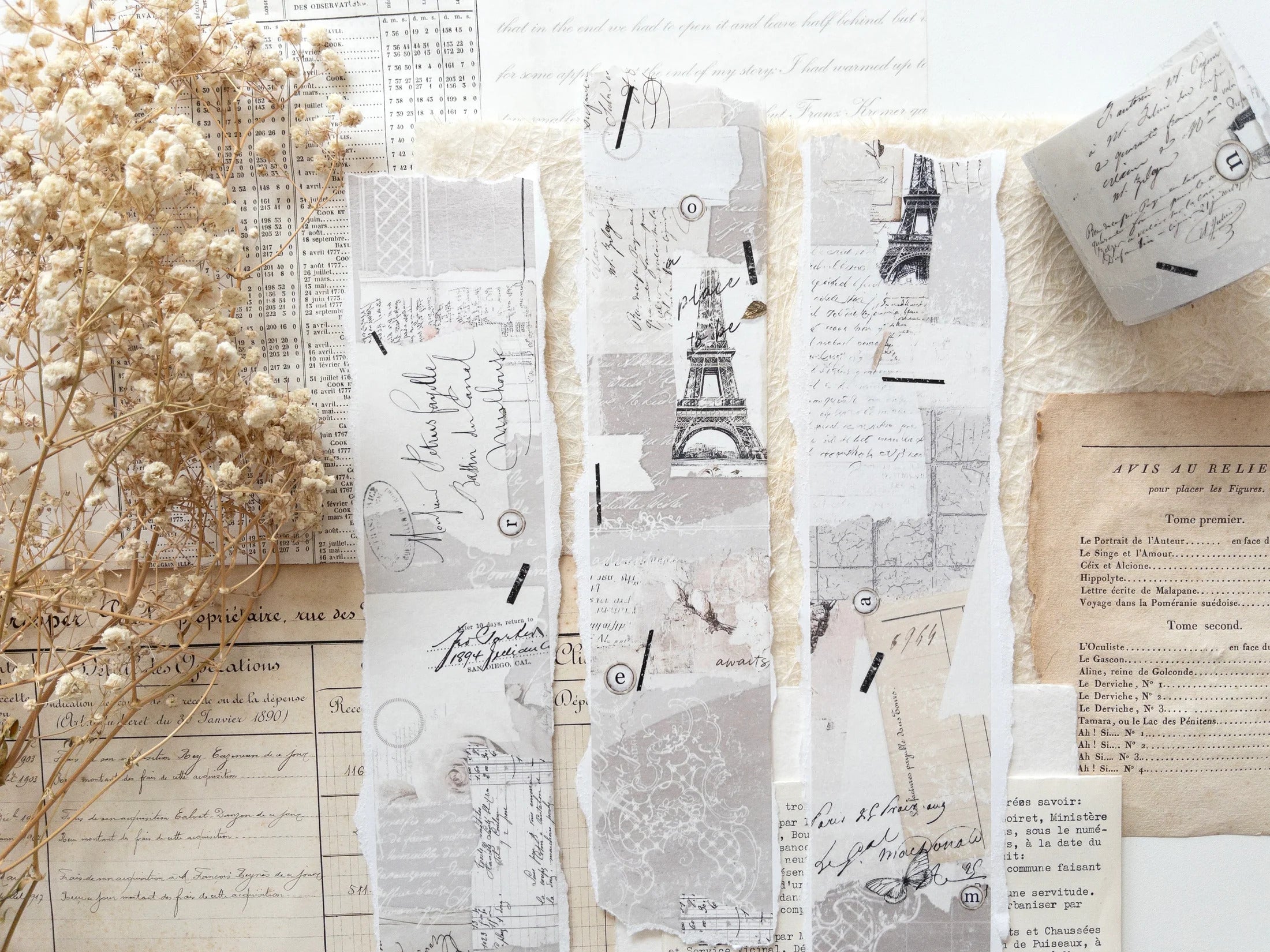 Decorative washi tape with vintage designs, particularly focus the Eiffel Tower, on a white surface with dried flowers.