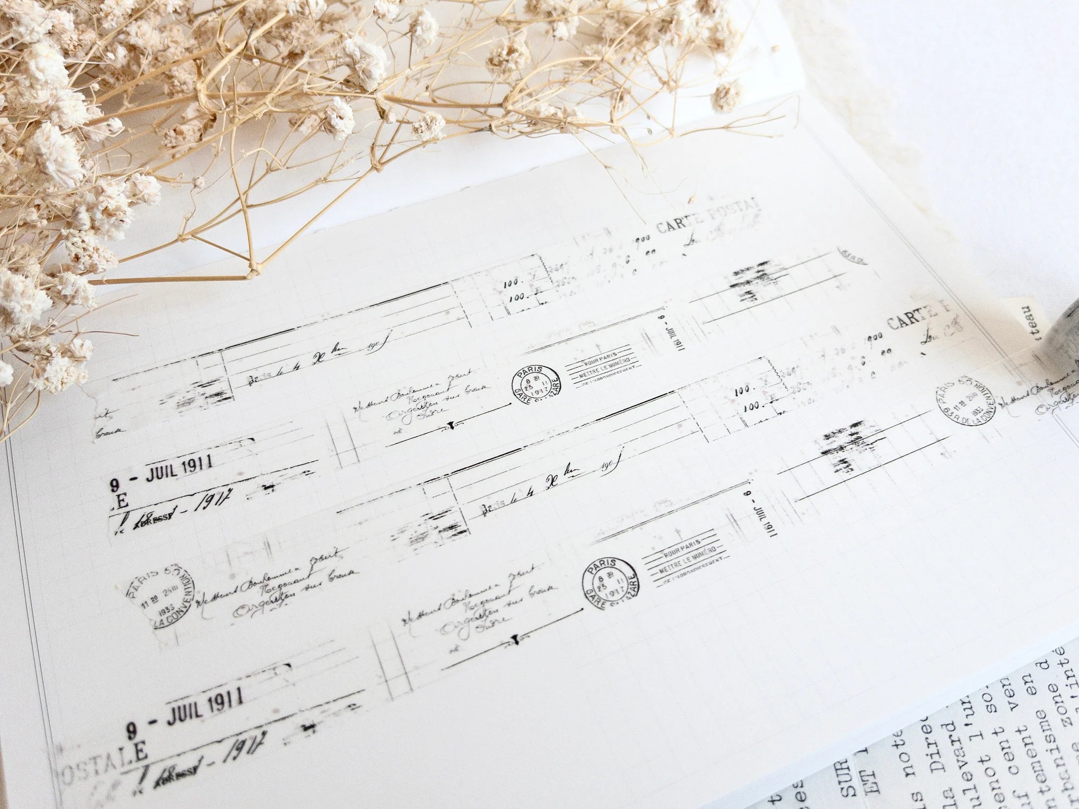 Washi tape with distressed vintage elements on light background with dried flowers next to it