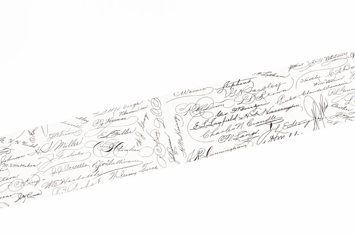 A close-up of a white washi tape covered with many small black handwritten signatures and cursive writing, shown diagonally across the frame.
