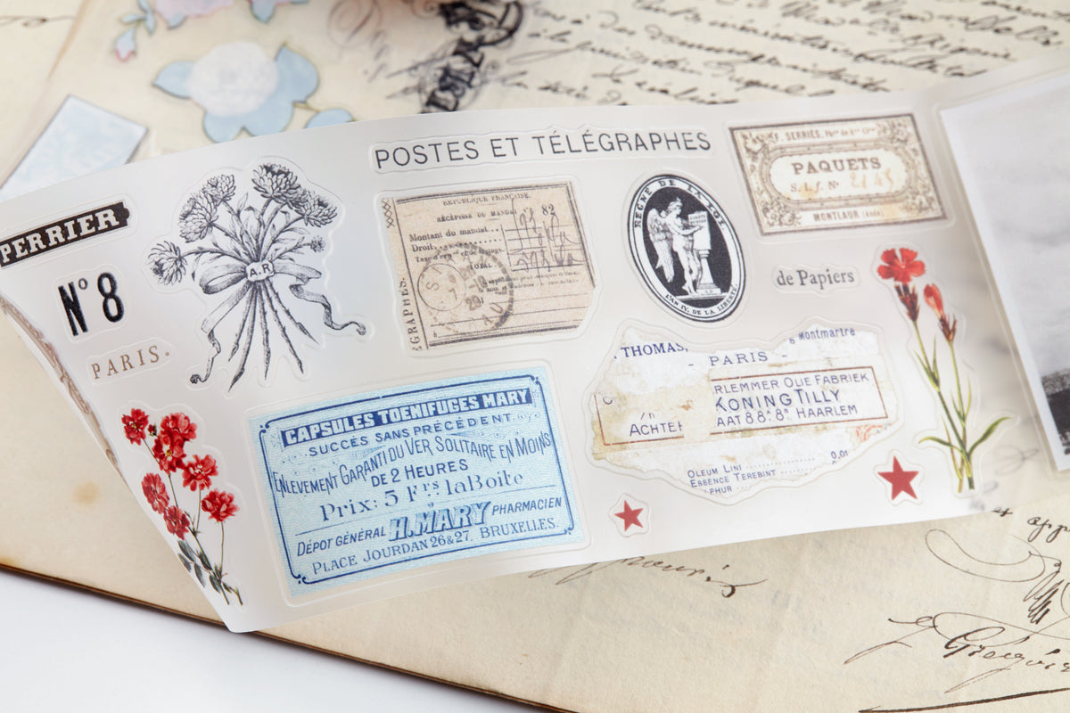PET tape with pre-cut vintage-style decorative stickers such as illustrated labels, postage stamps, numbers, and antique typography, laid over a background of old handwritten letters and papers.