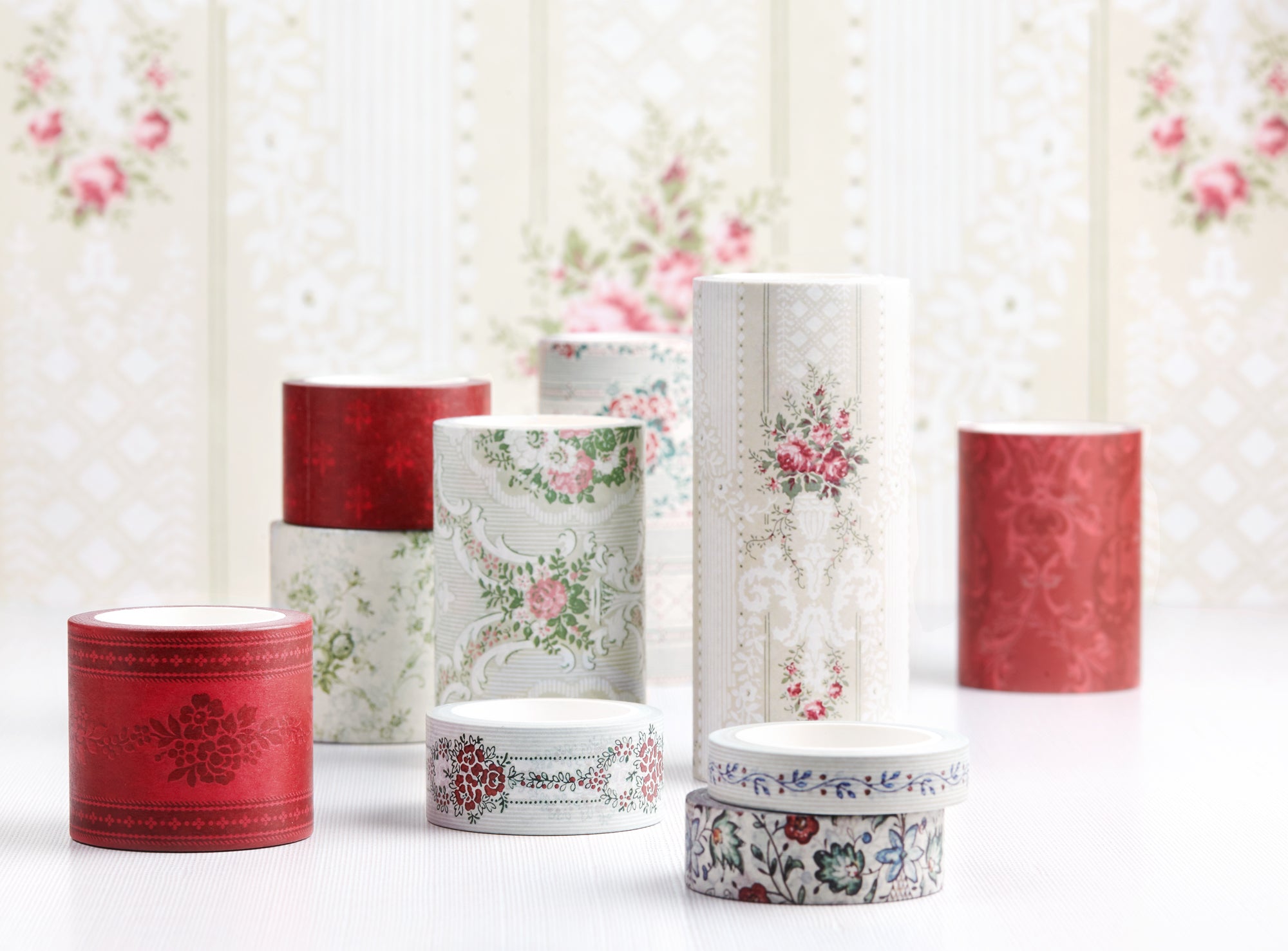 A collection of decorative washi tapes with various floral and damask patterns, displayed on a white surface against a patterned cream background.