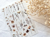 Sheet of floral stickers with dried flowers on a white surface
