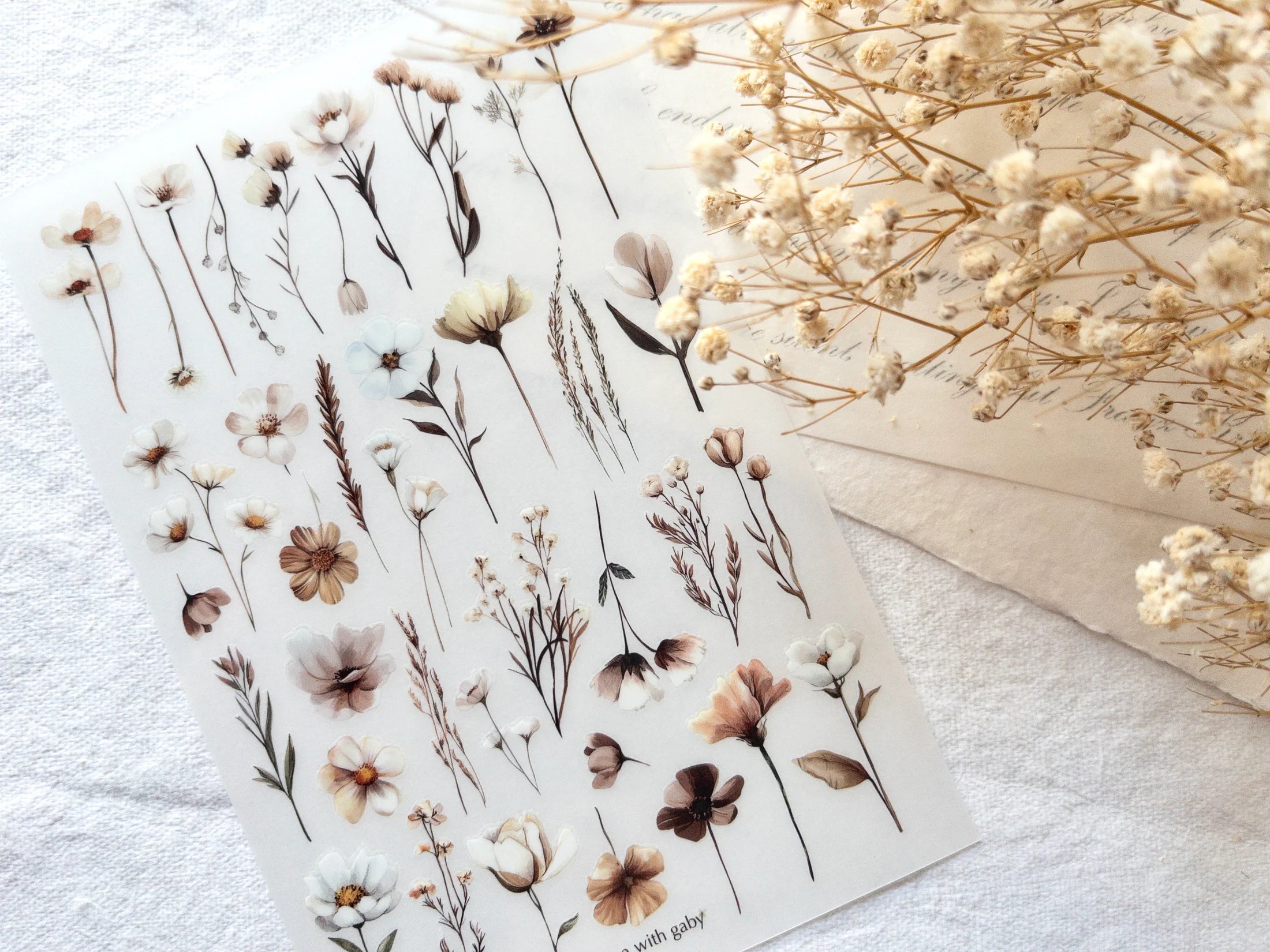 Sheet of floral stickers with dried flowers on a white surface