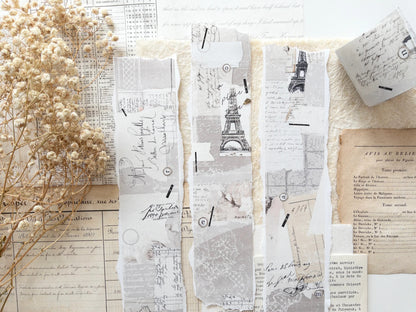 Decorative washi tape with vintage designs, particularly focus the Eiffel Tower, on a white surface with dried flowers.