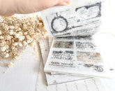 Hand flipping through sticker book with vintage-style designs on a light background