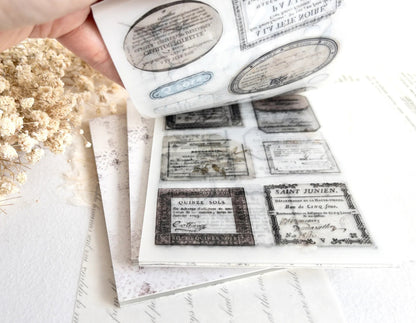 Hand flipping through sticker book with vintage-style designs on a light background