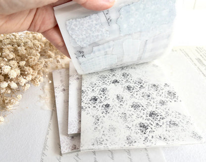 Hand flipping through sticker book with floral designs on a light background