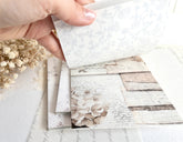 Hand flipping through sticker book with floral designs on a light background