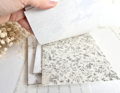 Hand flipping through sticker book with floral designs on a light background