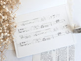 Washi tape with distressed vintage elements on light background with dried flowers next to it