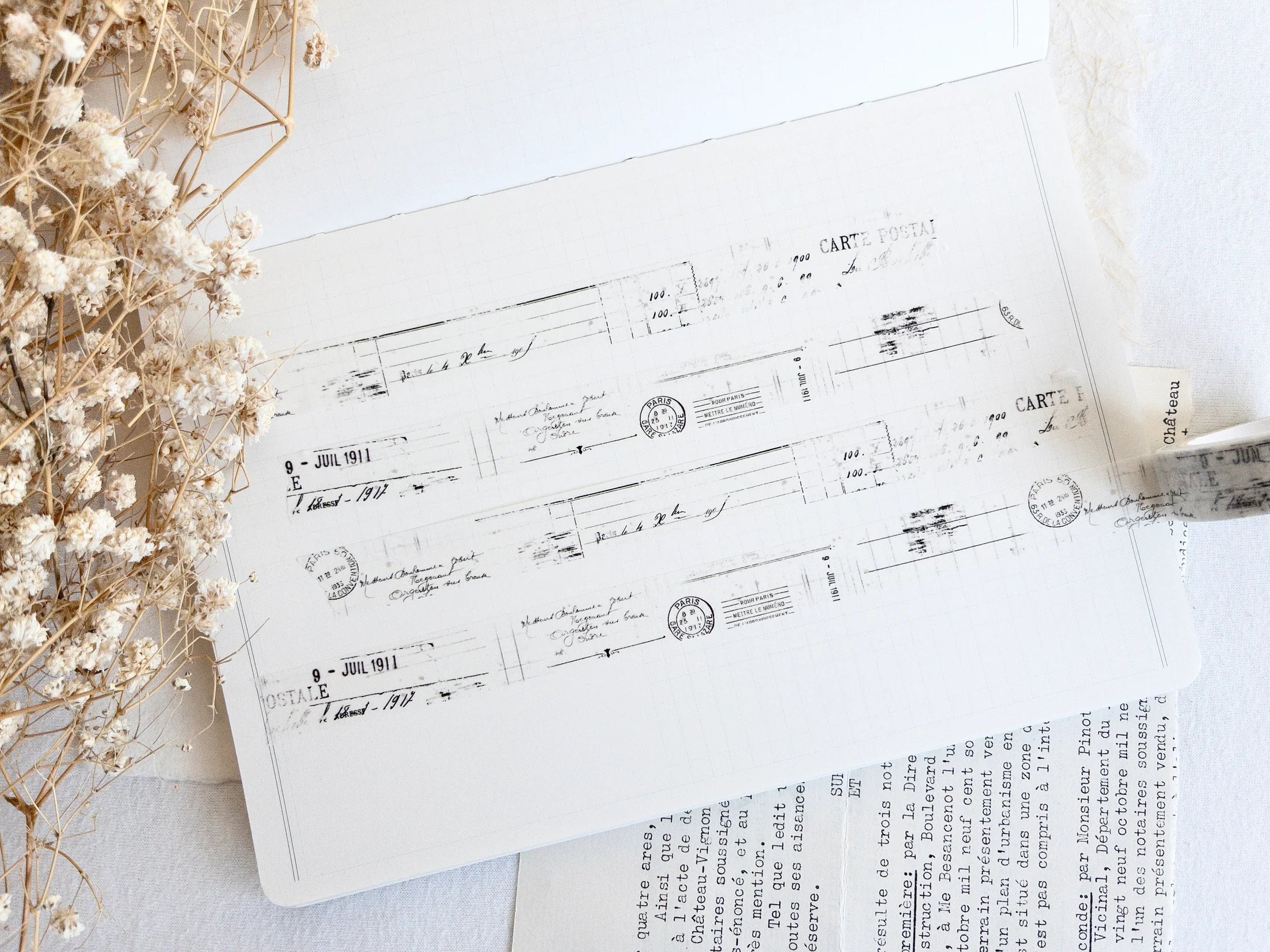 Washi tape with distressed vintage elements on light background with dried flowers next to it