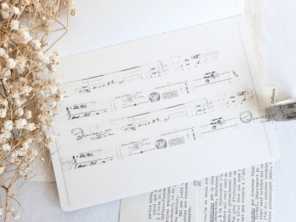 Washi tape with distressed vintage elements on light background with dried flowers next to it