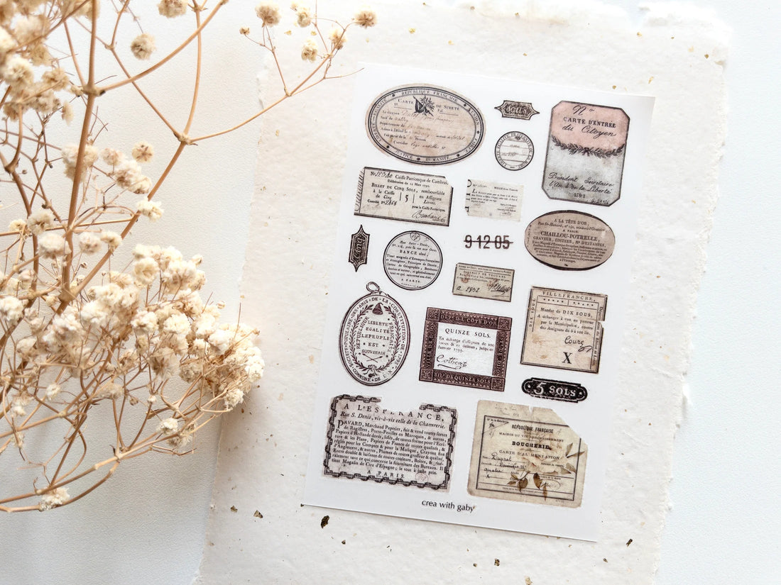 Collection of vintage-style rub-on transfers on a textured surface with dried flowers.