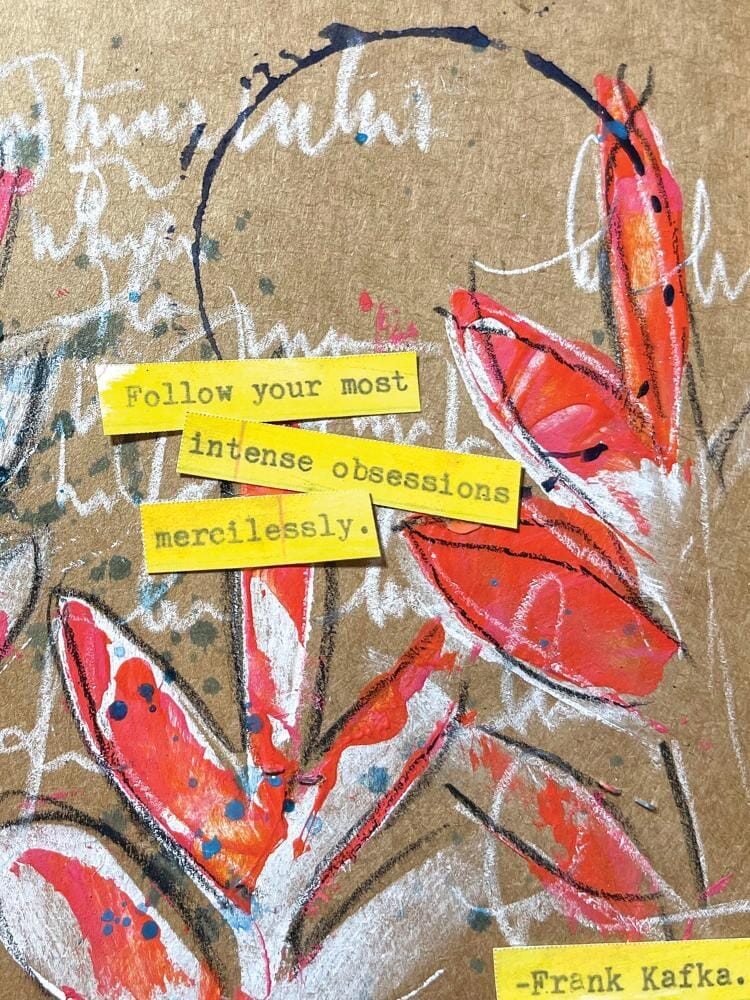 A close-up of a textured kraft paper print featuring abstract red and orange floral brushstrokes, white script writing, small blue paint splatters, and yellow paper tabs with text including &