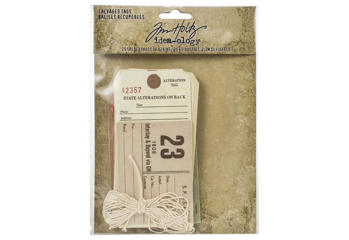 A package of Tim Holtz Ideaology Salvaged Tags, containing 25 paper tags and 3 yards of white string, shown in its original retail packaging against a textured beige background.