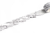A close-up of a washi tape strip of vintage French railway stamp paper showing printed text and stamps on a plain white background.