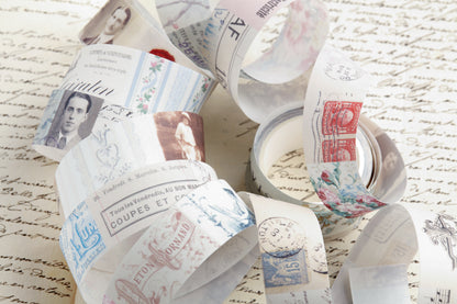 A collection of decorative washi tape printed with vintage postage stamps, postmarks, and classic portraits, arranged on top of a background of handwritten paper.