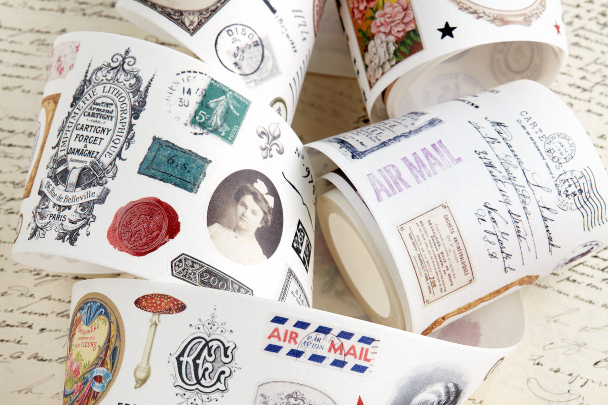Washi tape with pre-cut vintage-style decorative stickers such as illustrated labels, postage stamps, numbers, and antique typography, laid over a background of old handwritten letters and papers.