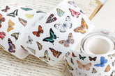 A roll of pre-cut washi tape featuring a colorful vintage butterflies on a white background, styled on top of antique handwritten book pages.