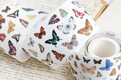 A roll of pre-cut washi tape featuring a colorful vintage butterflies on a white background, styled on top of antique handwritten book pages.