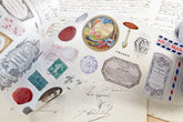 PET tape with pre-cut vintage-style decorative stickers such as illustrated labels, postage stamps, numbers, and antique typography, laid over a background of old handwritten letters and papers.