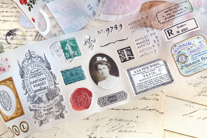 PET tape with pre-cut vintage-style decorative stickers such as illustrated labels, postage stamps, numbers, and antique typography, laid over a background of old handwritten letters and papers.