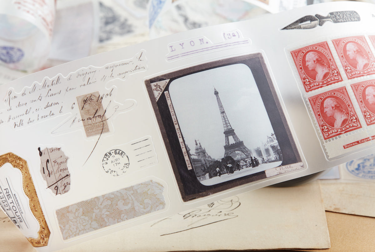 PET tape with pre-cut vintage-style decorative stickers such as illustrated labels, postage stamps, numbers, and antique typography, laid over a background of old handwritten letters and papers.