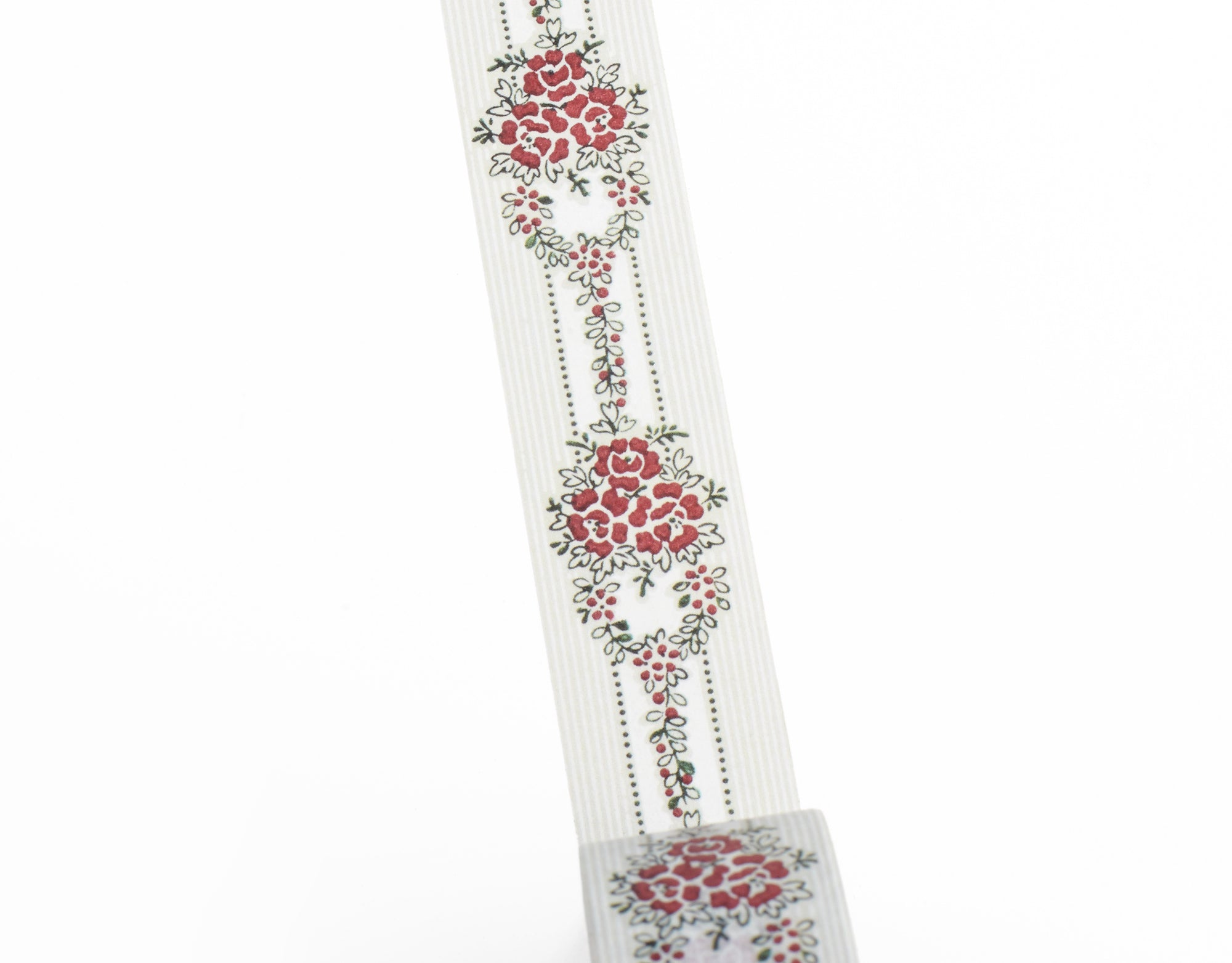 A close-up of a decorative wasi tape featuring a repeating vertical floral pattern with red flowers, green leaves, and dotted lines, shown against a plain white background.