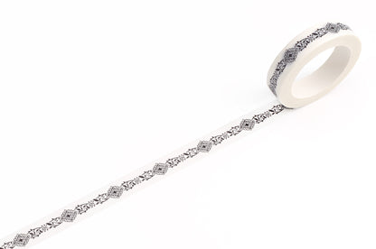 A roll of white decorative tape with a repeating black filigree pattern, shown unrolled on a clean white background.