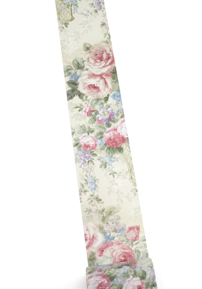 A close-up of a washi tape with a vintage floral print featuring pink and red roses, green leaves, and small blue flowers on a light cream background.
