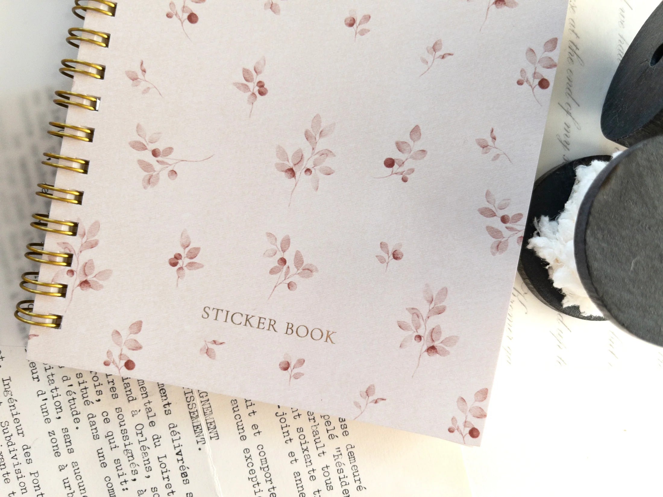 Sticker book with floral pattern on cover, placed on a surface with old pages.