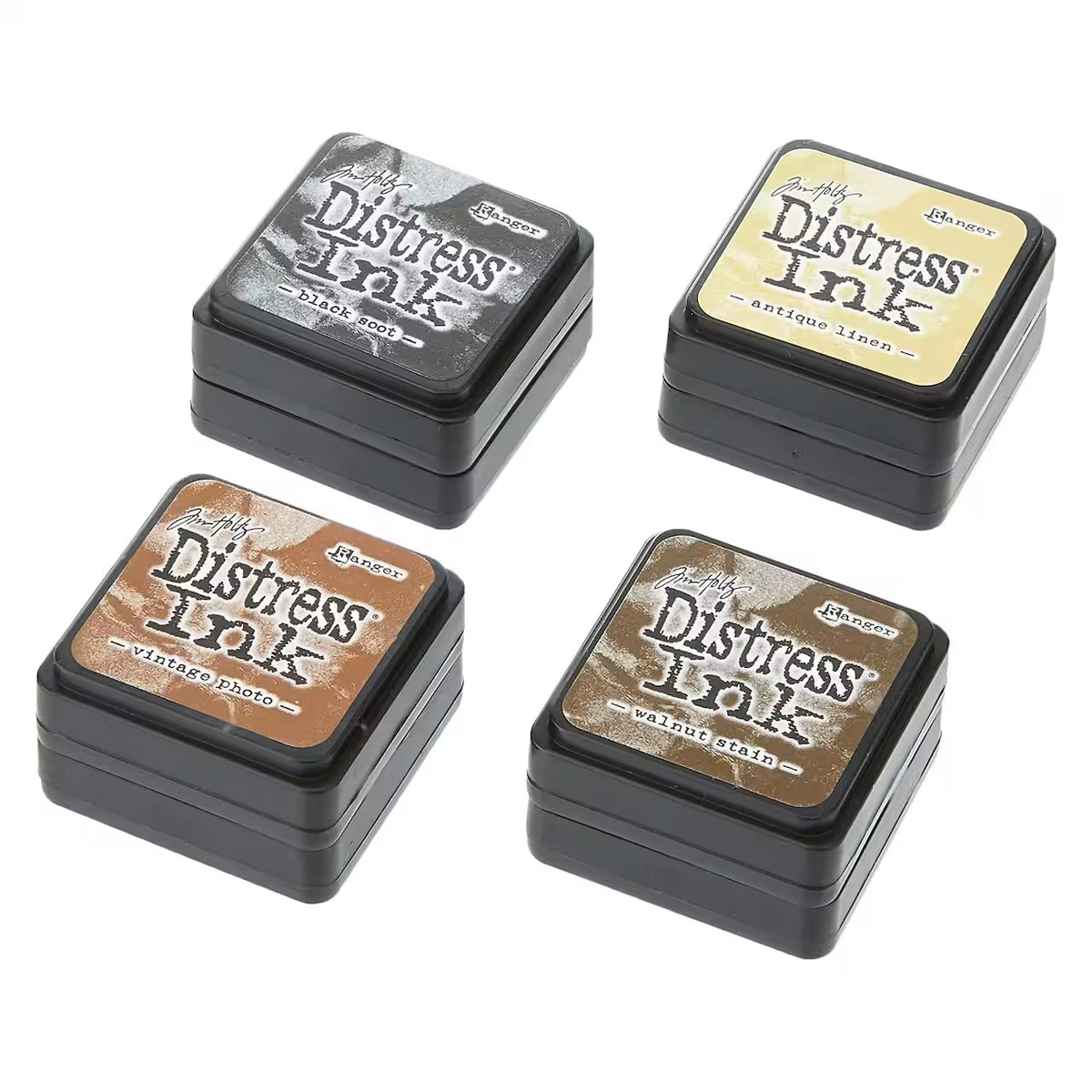 Four Mini Distress Ink pads in black square containers arranged on a white background. The labels show different ink colors: black soot, antique linen, vintage photo, and walnut stain.