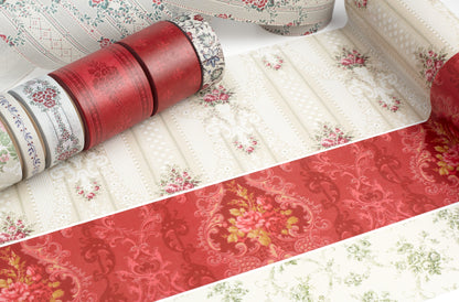 A close-up of patterned wallpaper washi tape rolls, showing cream backgrounds with red, pink, and green floral and damask-style motifs.