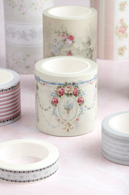 A collection of decorative washi tapes with vintage floral and striped patterns, displayed on a soft pink surface.