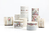 A group of decorative washi tape rolls with floral and geometric patterns, arranged on a clean white background.